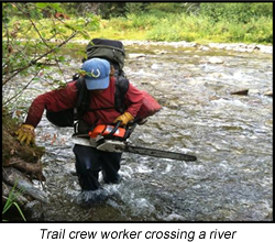 Trail crew member crossing a river