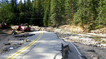 Flood damage to a paved road in the forest.