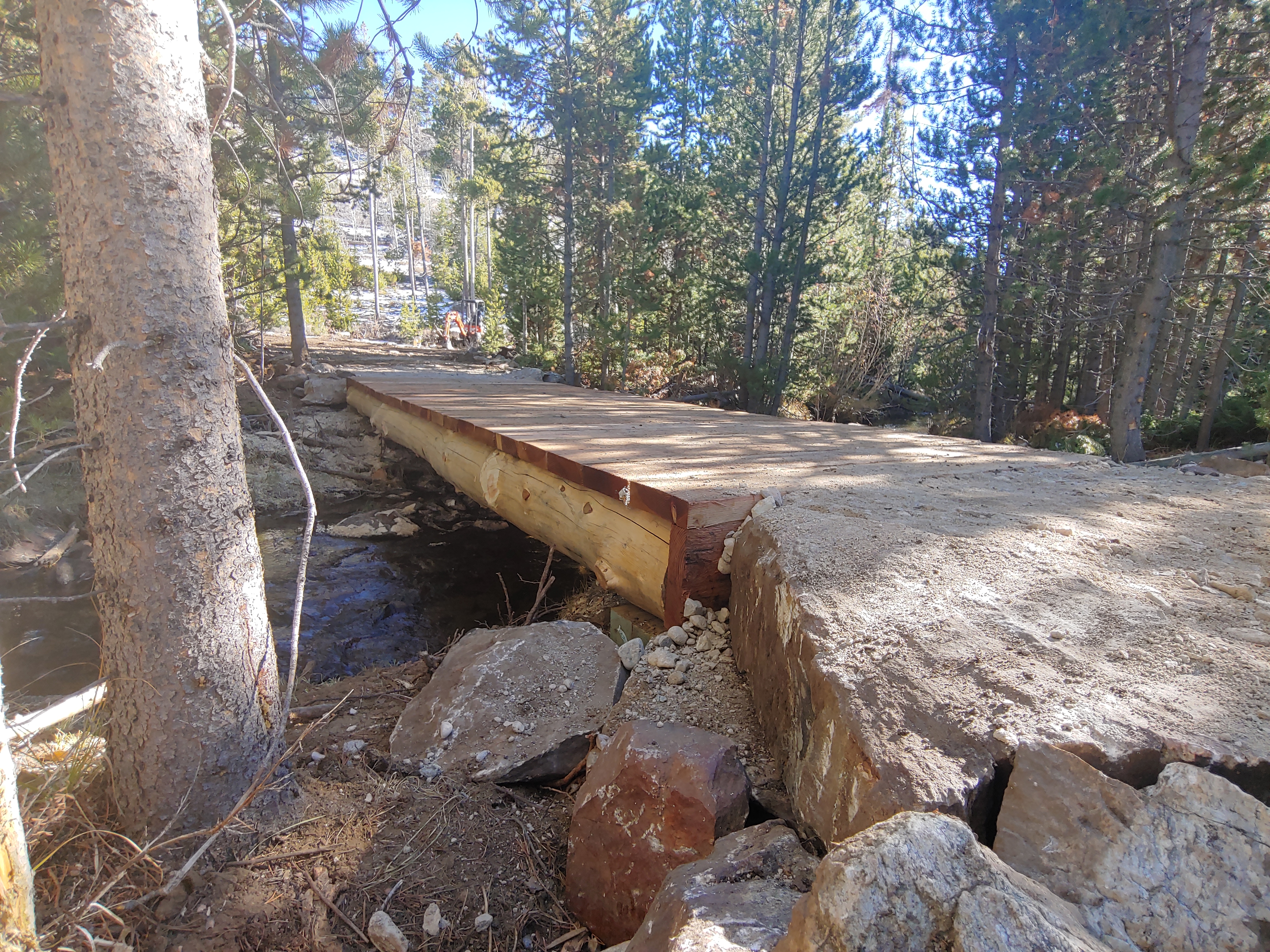 A picture of a wood constructed bridge in a dense forested area.