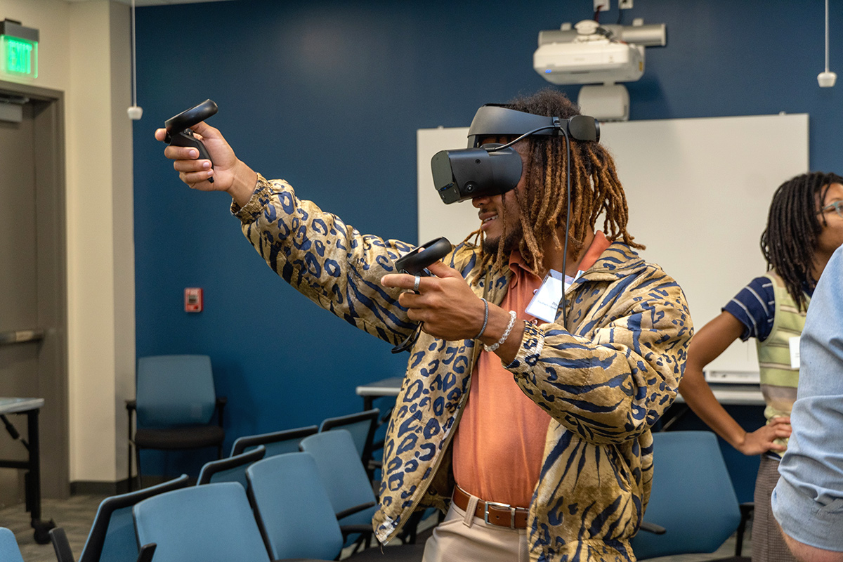 A person using virtual reality hardware, including a headset and two hand devices, in a conference room.