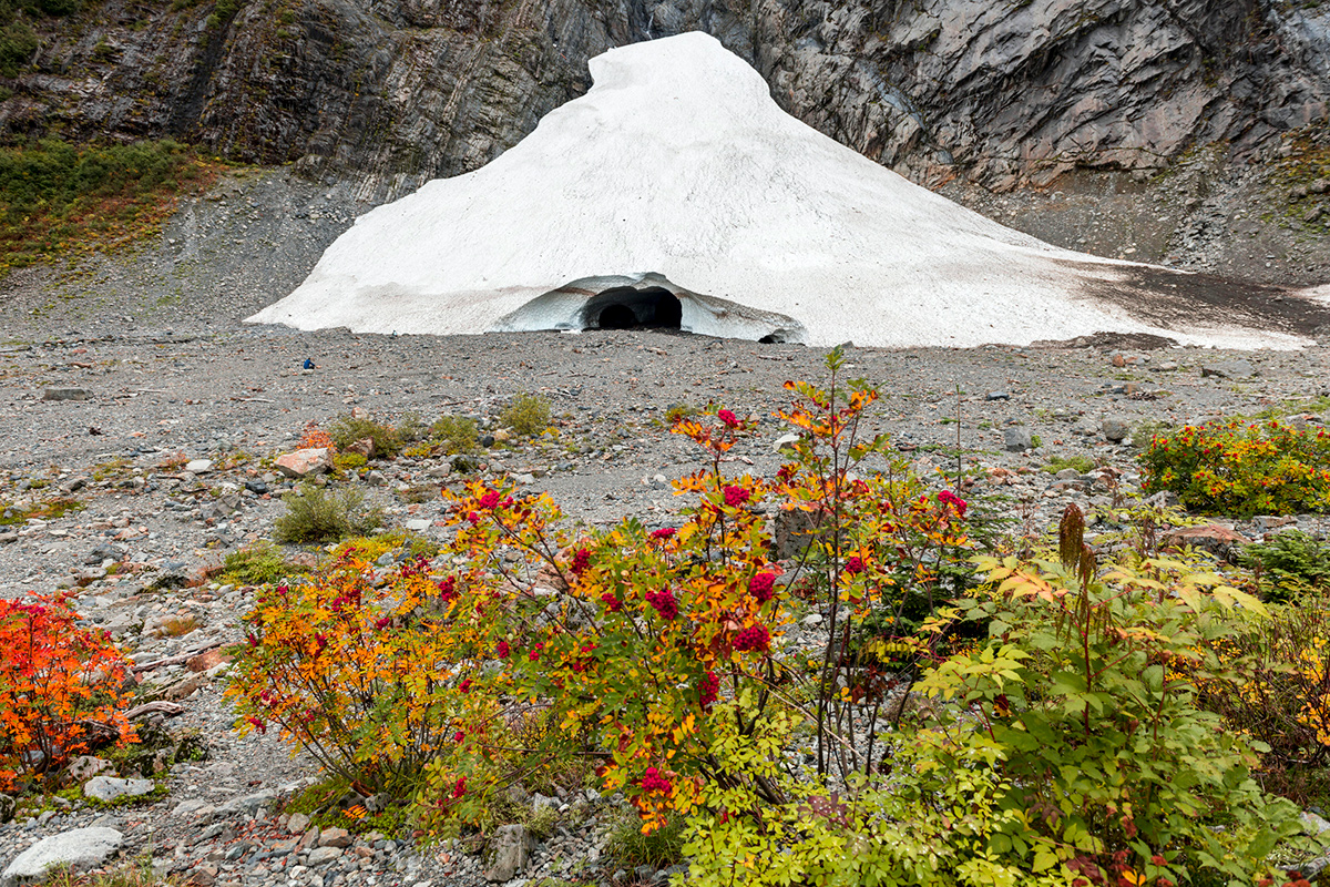 A small ice cave in a small ice feature at the base of a rock face.