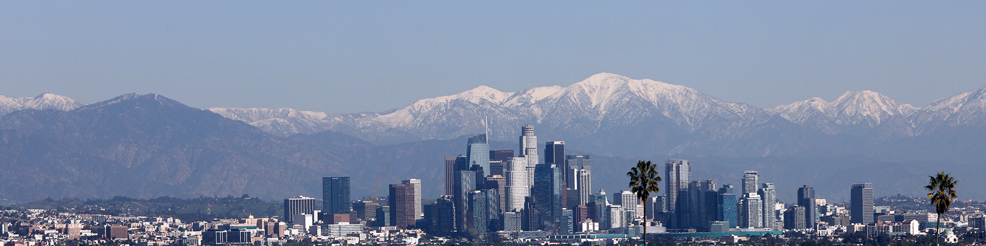 City skyline with snow-capped mountains behind.