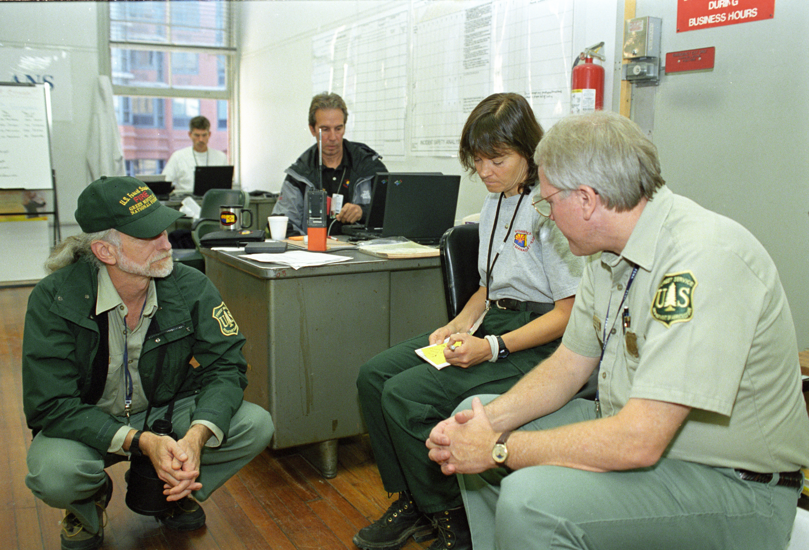 Forest Service and incident management employees in a room discussing things.