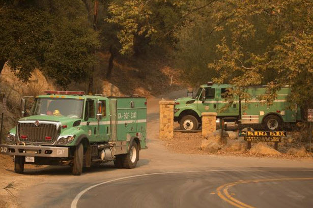 Two green USDA Forest Service fire engines parked along a paved road. A sign in the background reads "PARMA PARK."