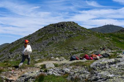 A crewmember carries rocks to the work site on Crawford Path, New Hampshire, with the summit of Mount Washington in the background