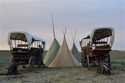Two wagons and three tipis set up on a grassy plain at the BLM's National Trails Interpetive Center.
