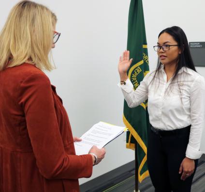 A woman swears in another woman; Forest Service flag on the background
