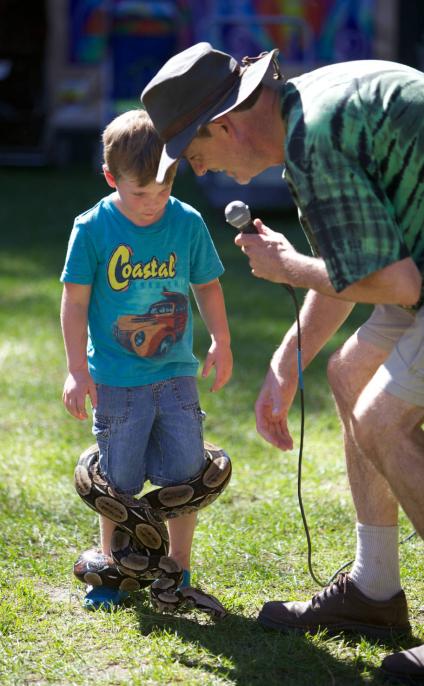 Educator stands with young child who has snake wrapped around his legs.