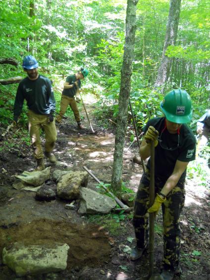 Youth conservation corps members use pick mattock, rounded shovel and other hand tools to restore trail.