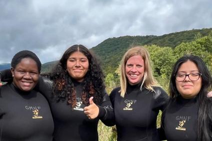 Group photo: Students & Forest Service employee in wetsuits emblazoned with GMNF Seavenger and a logo.