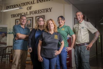 A group of employees stand in front of a wall with text as International Institute of Tropical Forestry.