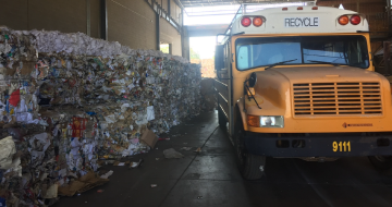 Bundled recycling on large pallets next to a school bus used to haul recycling