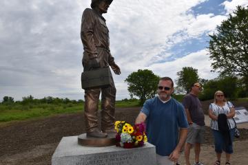 Man lays bouquet of flowers on base of Joliet Arsenal statue.