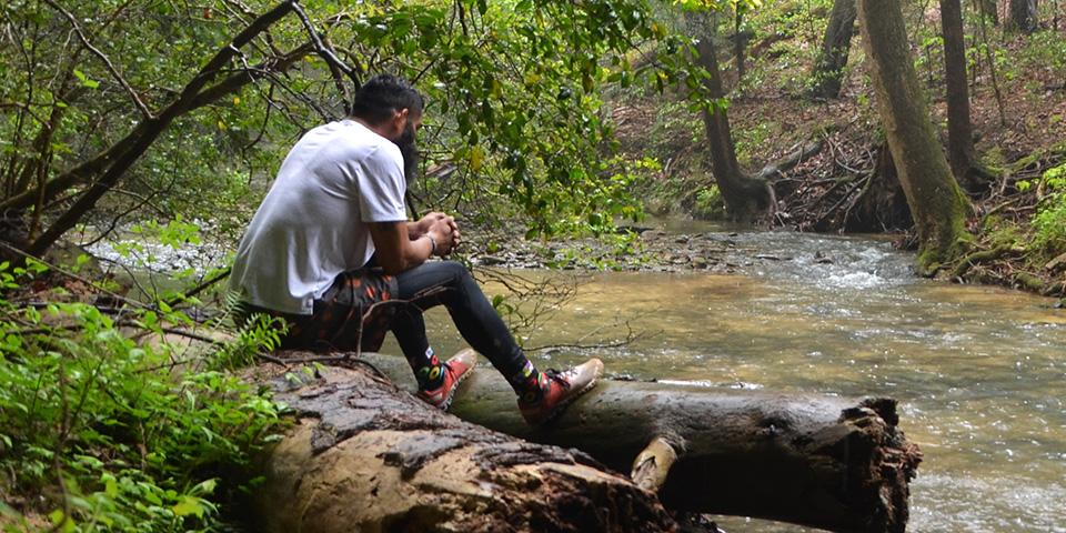 man sitting on log looking at river