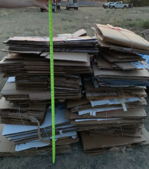 Large pile of cardboard with measuring tape in front to show height of pile.
