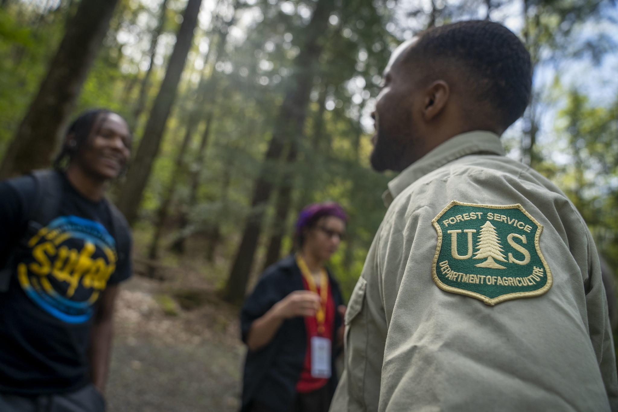 A recruiter speaks to a job seeker on a field trip in the forest.