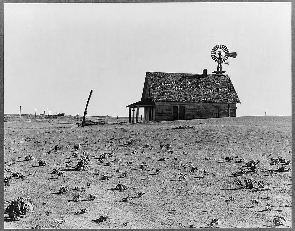 A lone farm house with dust-storm ravaged land all around it in a bleak view of the Dust Bowl’s ravages.