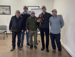 Group photo: Five people wearing baseball caps stand in a conference room. One holds a small, stuffed Smokey Bear.