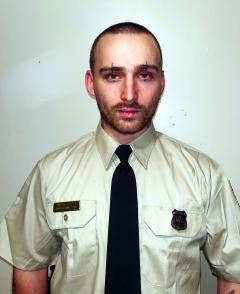 Simon Austin in Forest Service uniform against a white backdrop.