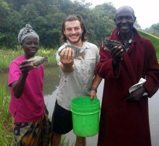 Two men and a woman hold a fish in each of their right hands (which are extended towards the camera) and smile. 