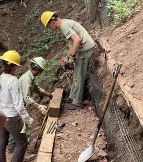 A picture showing three trail workers working to repair a trailer area.
