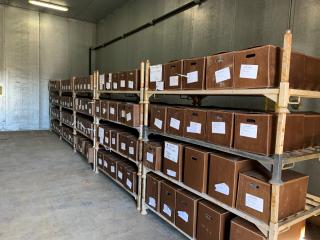 A picture of warehouse shelving area with several boxes placed on each shelf and all boxes have a white label in front.