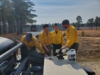 Firefighters gather around the hood of a truck talking