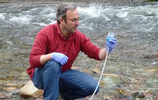Image of Forest Service Scientist collecting a water sample.