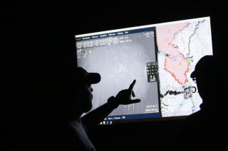 A picture of two people looking at a digitized, large wildland firefighting map that has been projected on a screen.