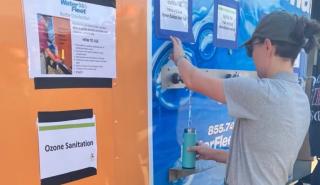A person filling their water bottle from a mobile water treatment trailer 