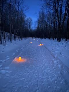 Luminarias light the snow-covered trail to Morgan Falls at twilight.
