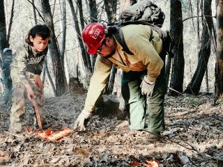 Beau Goodwin and his son Carter Goodwin use pitch sticks to start a prescribed burn at Inaam for Women’s Prescribed Fire Training Exchanges in Karuk Ancestral Territory. 