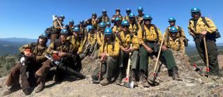 American River Hotshots of the USDA Forest Service in California gather for a group photo on a mountain peak after a hard day’s work.