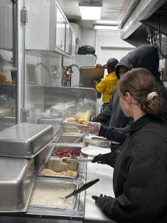Cooks standing by a food preap counter inside a mobile food kitchen