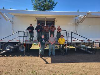 Group photo: A group of youn adults stnad outside the entrance to a mobile kitchen truck