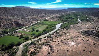 Aerial view of a vast landscape with roads, rivers, grasslands, farms and forested hillsides.