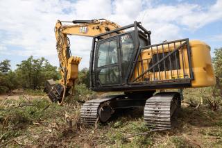 A piece of heavy equipment with arm extending in to the brush.