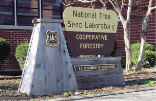 The National Tree Seed Laboratory, Cooperative Forestry sign on a wooden base, ouside of a brick building.