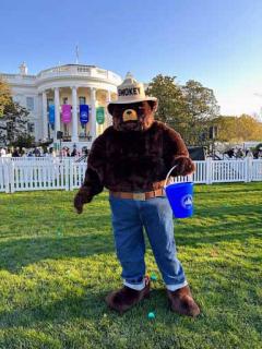  Image shows Smokey Bear holding a bucket standing on the White House lawn during the White House Easter Egg roll.