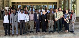 Group photo: Trainees, trainers and Zambian government official outside a building.