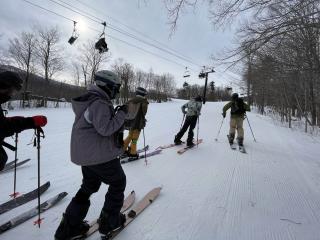 Young people traveling uphill in snow on splitboards. 