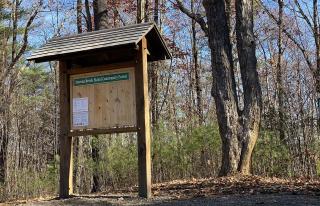 A covered notice board inside a community forest.
