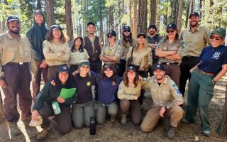 A group of trail maintenance professionals standing together for a group photo in a forest.