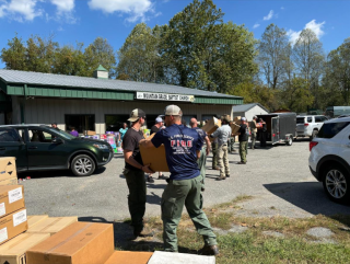 Image shows a group of people unloading boxes near a church.