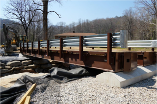 Image shows a steel temporary bridge placed in the ruins of a destroyed bridge.