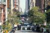 Green trees along both sides of a busy paved street in New York City.