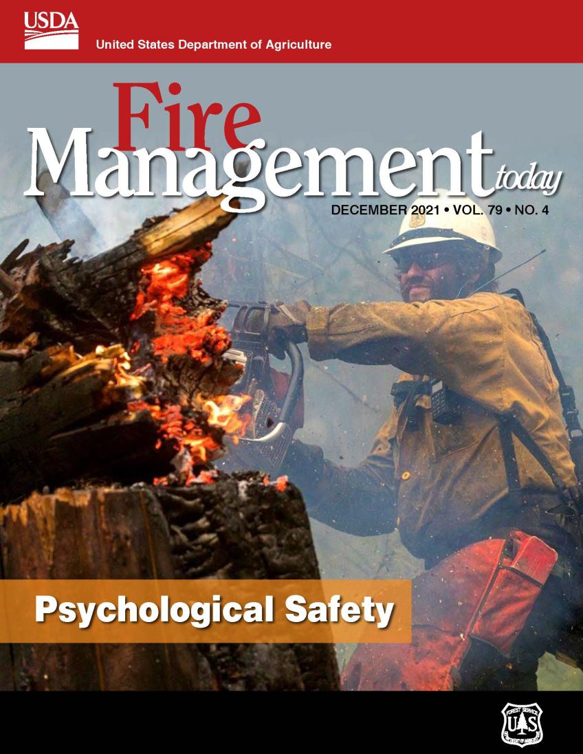 A picture of the front cover of Fire Management Today showing a firefighter using a chainsaw on a burning tree.