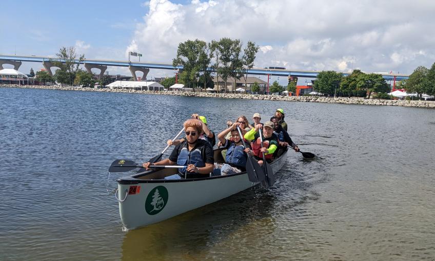 Students and adults paddling the Canoemobile on Lake Michigan.