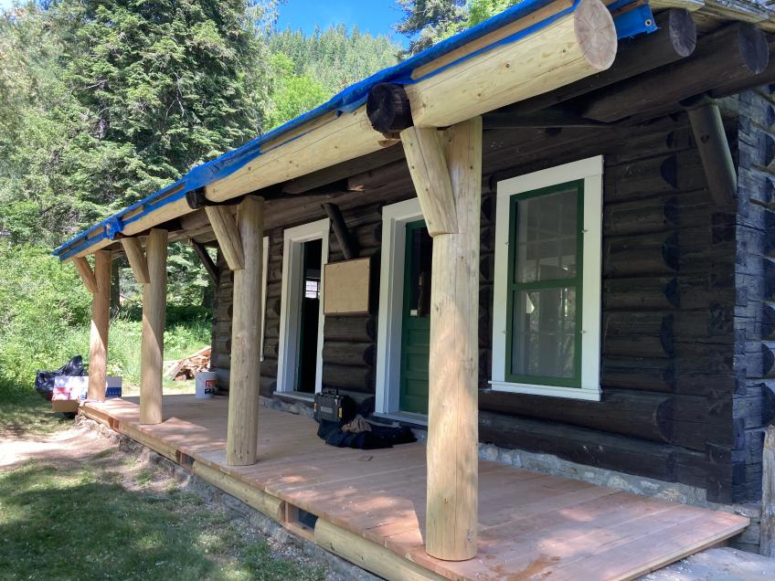 Taken from slight angle: visitor's center restoration includes new sill log and vents, porch decking, columns and porch roof purlin. The new wood is light against the dark logs of the center.