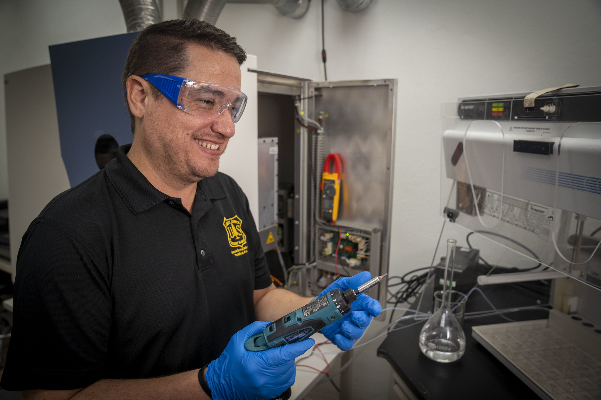 A researcher prepares to work with tools in a lab.
